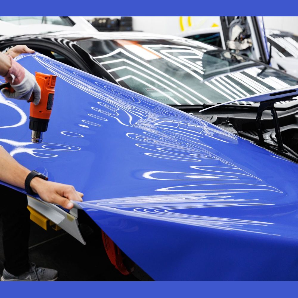 Blue wrap film being heated and stretched onto a hood