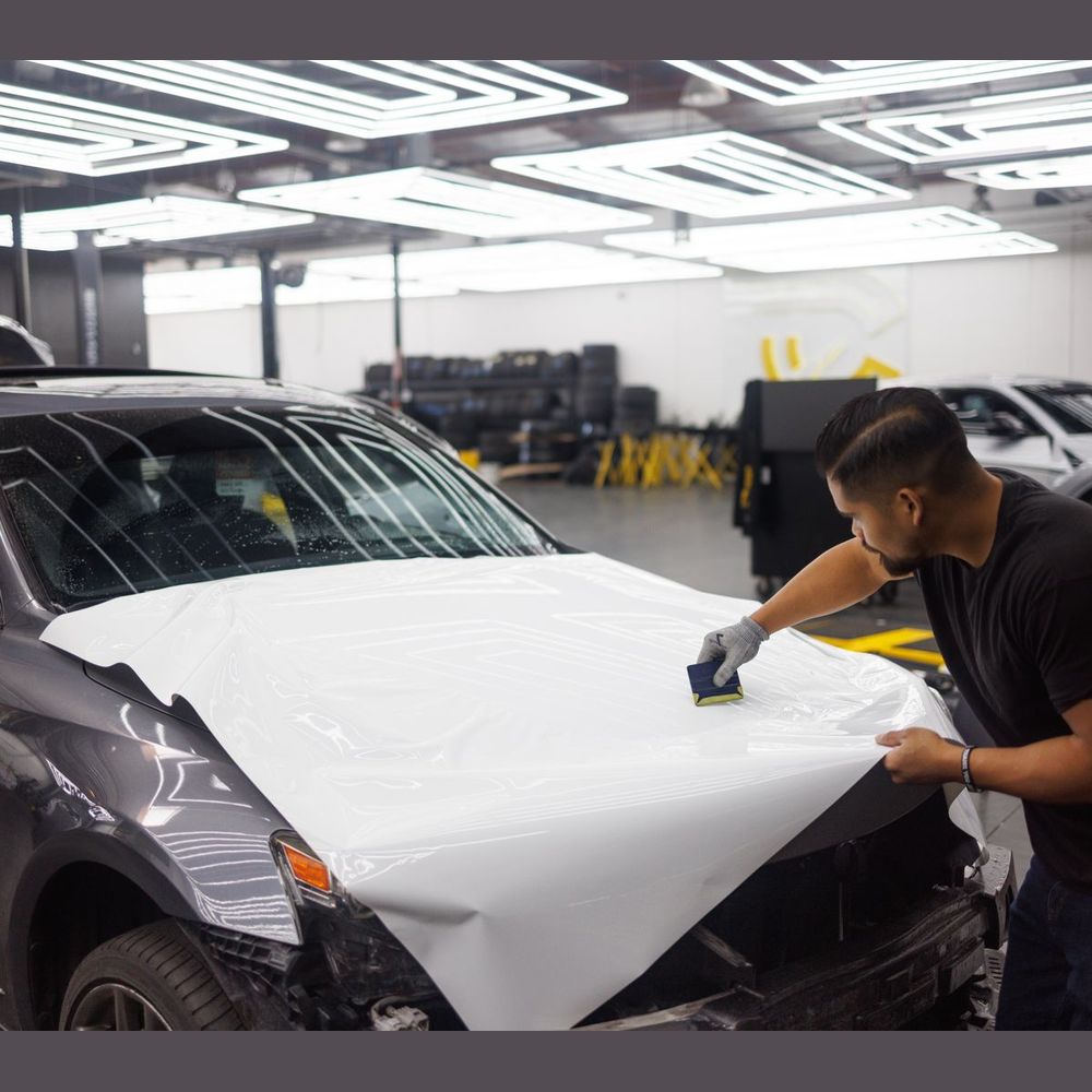 Installer applying vehicle wrap film to a car hood