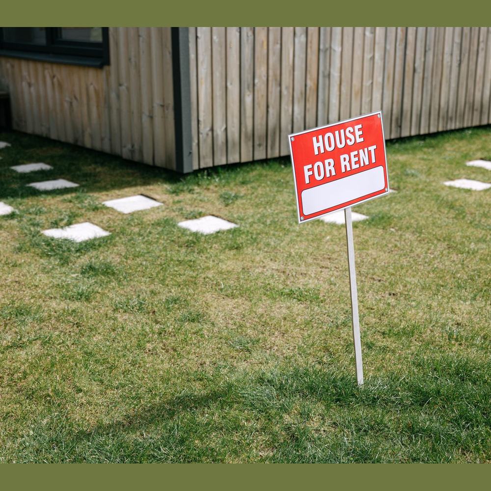 Red and white yard sign on a wire stake in a lawn