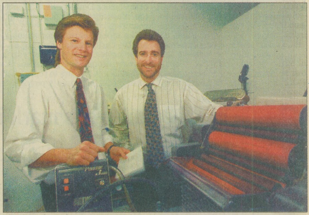 Picture of new owners of The Printing Factory in 1996 in front of a printer taken by the Daily Herald. 10/1/1996.